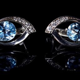 Image of Silver earrings with blue Topaz isolated on a black background.