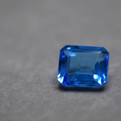 a 12 carat swiss blue topaz gem on a grey surface in white light