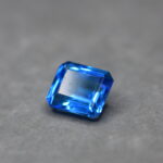 a 12 carat swiss blue topaz gem on a grey surface in white light