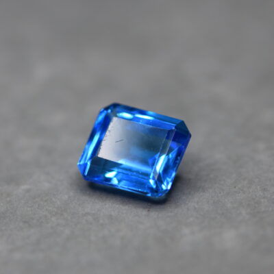 a 12 carat swiss blue topaz gem on a grey surface in white light