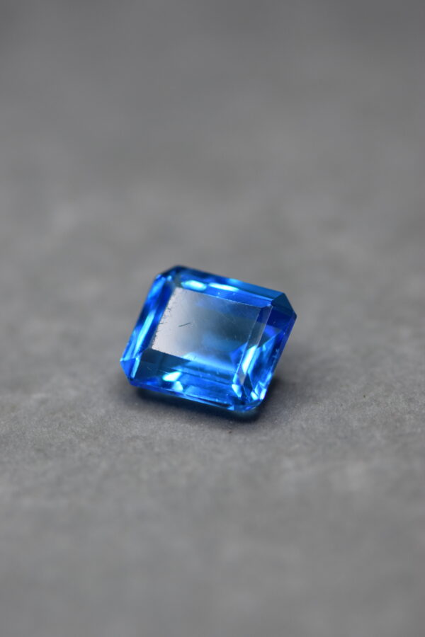 a 12 carat swiss blue topaz gem on a grey surface in white light